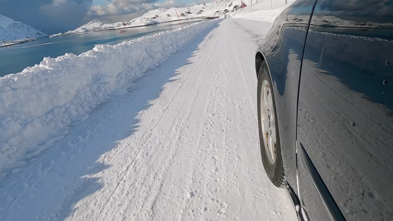 A car drives through snow on a picturesque Norwegian road