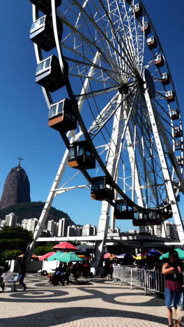 ferris wheel with christ the redeemer and cityscape in rio de janeiro