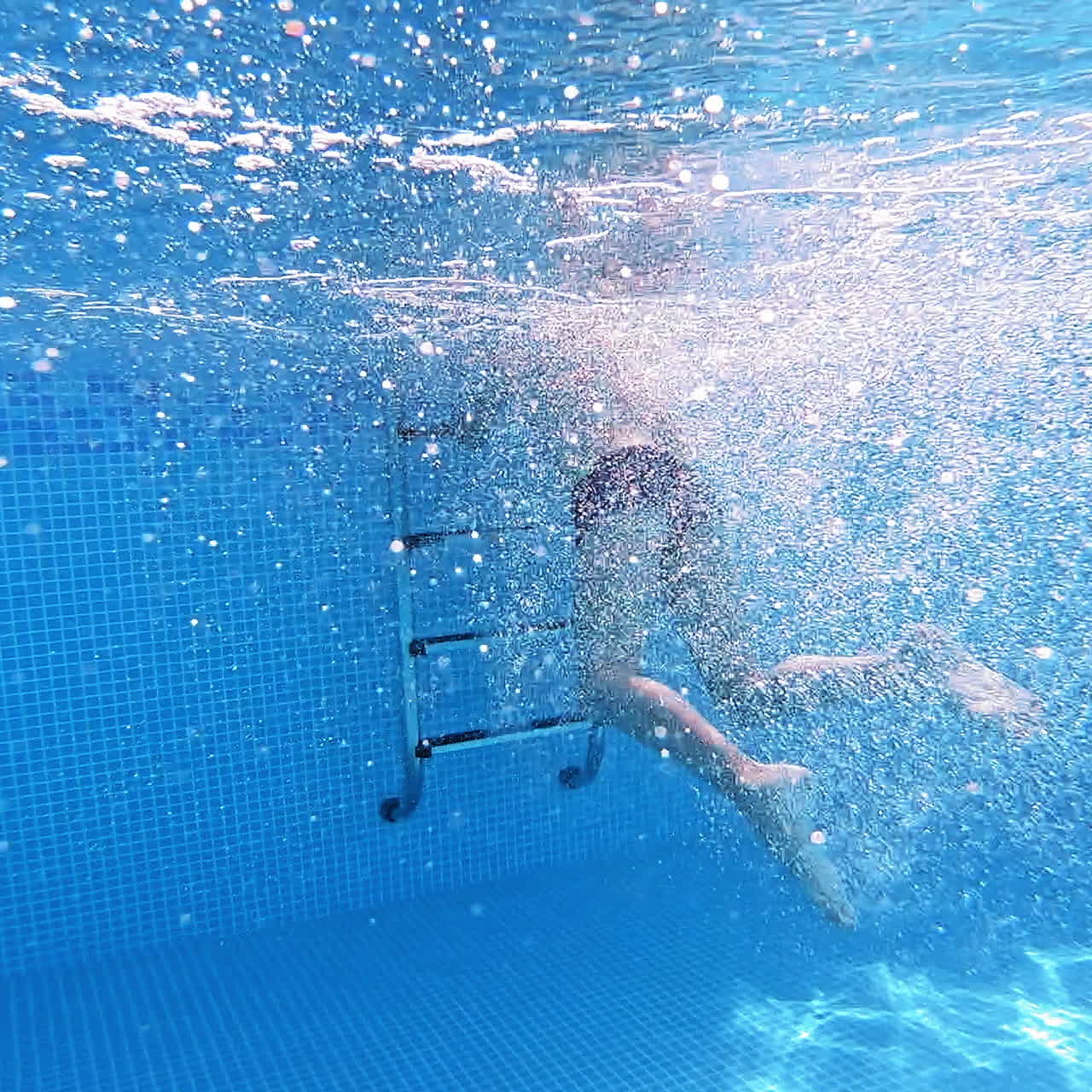 Boy's jump into the deep water making many bubbles. Young boy jumping underwater into the swimming pool. Underwater camera.