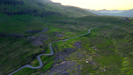 Aerial View of a Winding Mountain Road Through Green Landscapes