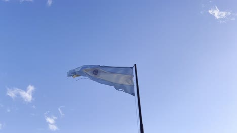 torn flag of argentina waving in the wind against blue skies, 60fps