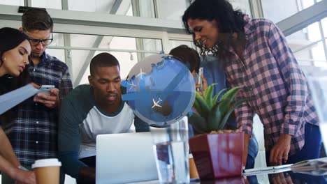 Animation-of-globe-rotating-over-happy-diverse-female-and-male-coworkers-using-laptop-in-office