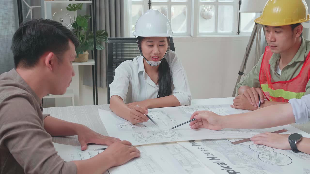 Three Asian Engineers With Helmets Presenting Work To A Man At The Office
