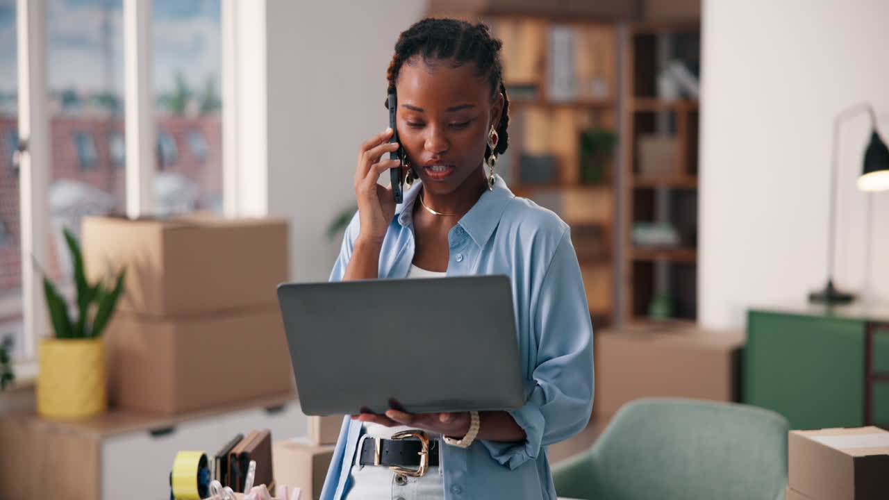 Donna al telefono con un portatile circondata da scatoloni