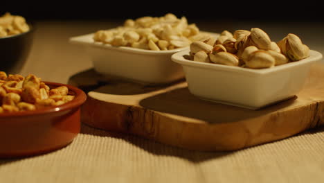 cerca de la mano eligiendo de cuencos de anacardos tostados secos cacahuetes y pistachos en el estudio