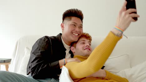 happy lgbtq+ couple taking selfies on the couch at home