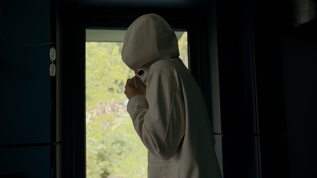 흰색 재킷을 입은 갈색 머리의 남자가 추운 산을 산책한 후 따뜻한 시골집에 들어갑니다. 그 남자는 겉옷을 벗고 집에 들어간다