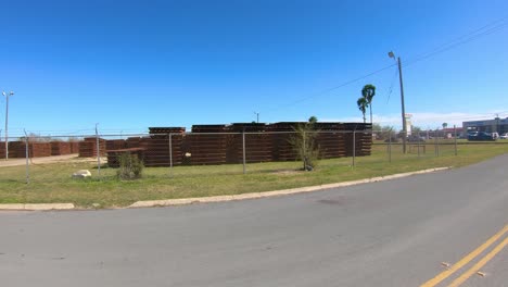 POV-driving-on-road-along-storage-area-for-panels-used-to-build-the-border-wall-between-Texas-and-Mexico