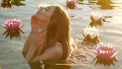 woman submerged in water with lotus flowers at golden hour