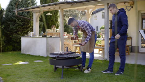 two men cooking barbecue outdoors