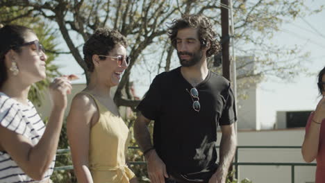 amigos sorridentes conversando enquanto bebem cerveja e comem pizza na festa no telhado