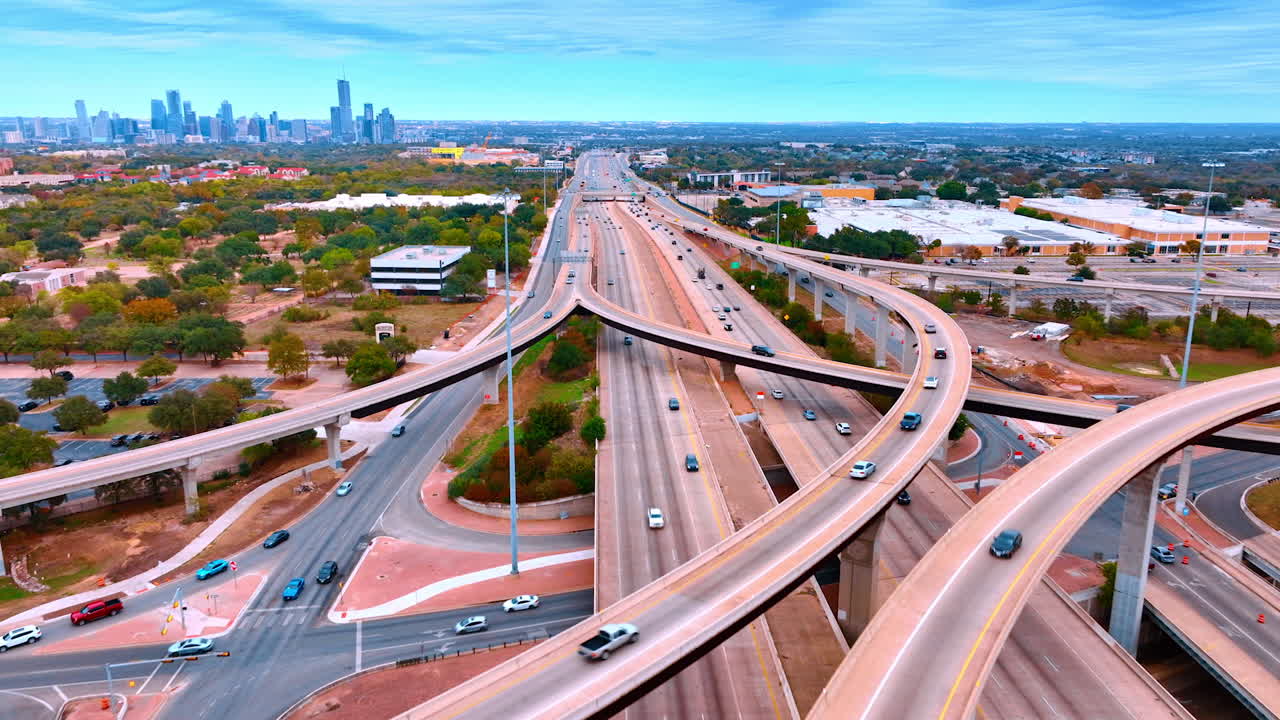 Austin, AS, 24 November 2025: Rekaman di atas jalan raya multi-jalur dengan penyangga di atasnya. Banyak mobil melaju di jalanan di sepanjang pemandangan kota modern