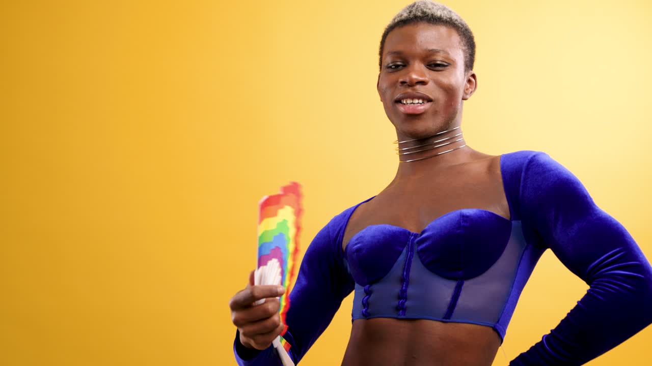 Persona Queer Sicura di Sé che si Sventola con un Ventaglio Arcobaleno su Sfondo Giallo