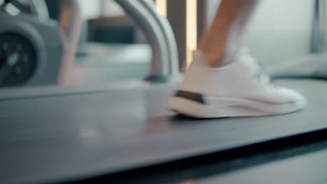 Closeup-male-feet-moving-on-treadmill-in-fitness-gym-in-slow-motion.