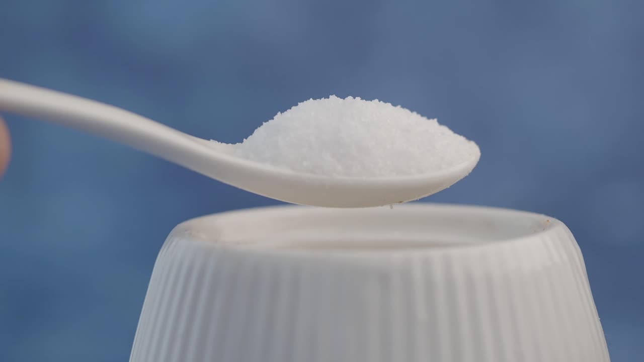 Salt on a spoon over a salt shaker