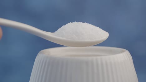 Salt on a spoon over a salt shaker