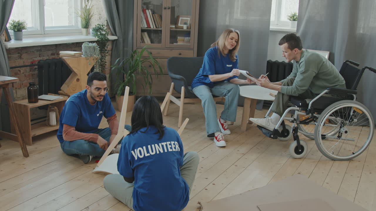 Group of Volunteers Assembling Furniture for Man in Wheelchair