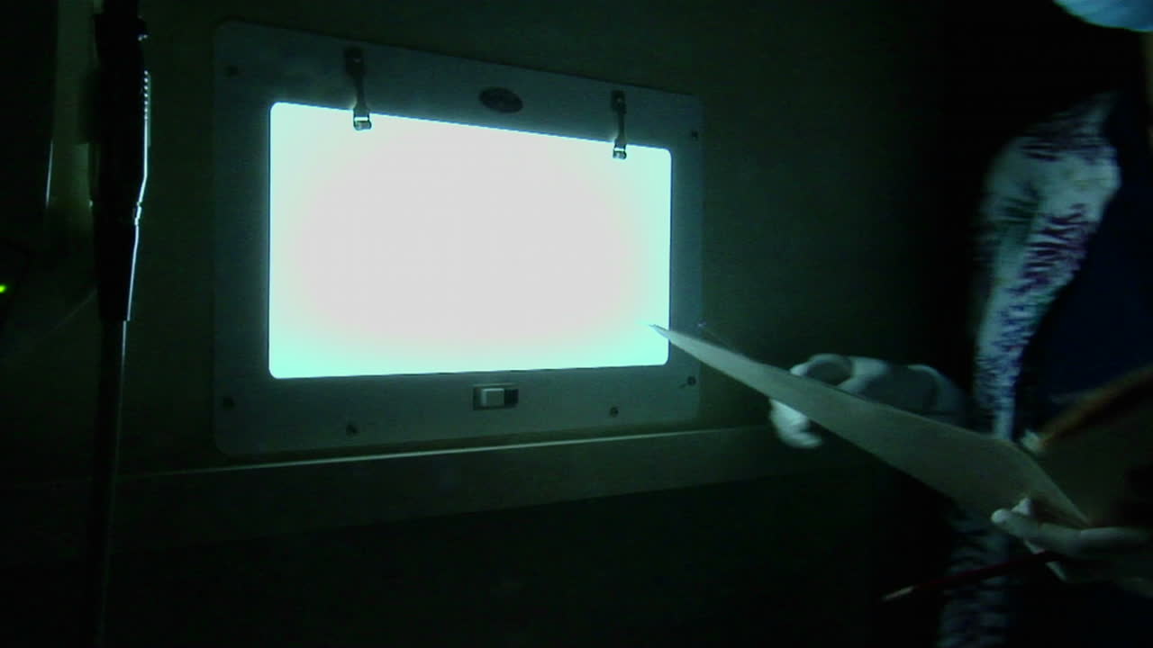 A dental hygienist looks at xrays in a darkened room 2