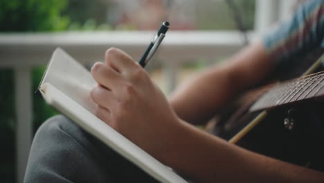 a musician writes a song on a porch