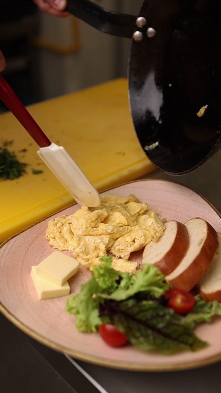 Chef Plating Fresh Scrambled Eggs with Bread and Salad