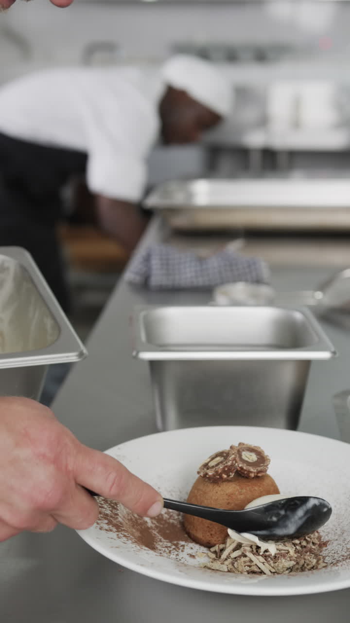 Caucasian male chef putting meal on white plate in kitchen, slow motion, vertical
