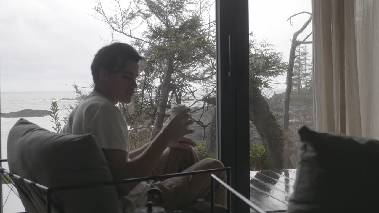 Giovane uomo che beve caffè caldo mentre è seduto su una comoda poltrona