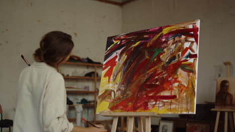 back view of female artist painting indoors. creative painter drawing in studio.