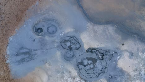 aerial top down : icelandic blue colored boiling mud pools in volcanic crater landscape of iceland - phenomenal aerial of natural sulfuric steam rising up into air