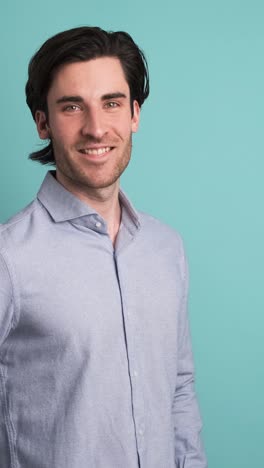 handsome man smiling at camera in blue studio
