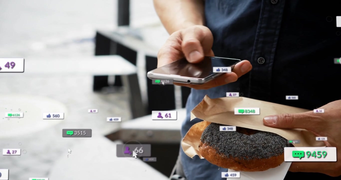 Man bringing phone up tapping screen while holding seeded bagel, notifications boosting engagement