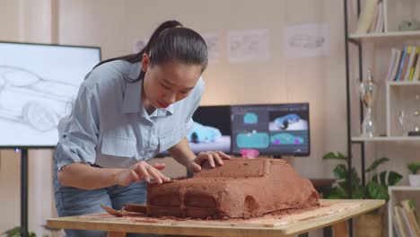 woman carving clay model of a car