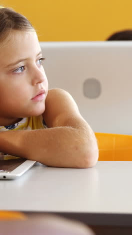 chica aburrida sentada en el escritorio en el aula