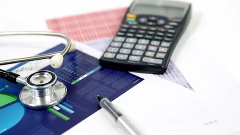 stethoscope, document, pen, and calculator on a white background