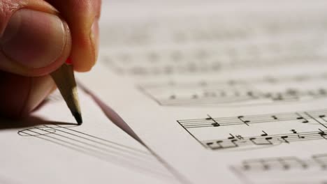a musician composer writes, on the empty pentagram, the notes of his new song or opera. the musician composes his new music.