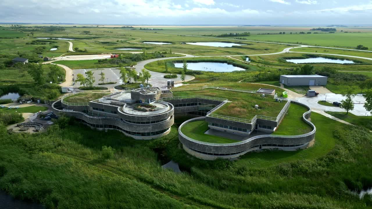 Aerial orbit showcases modern green roof building amid surrounding wetlands
