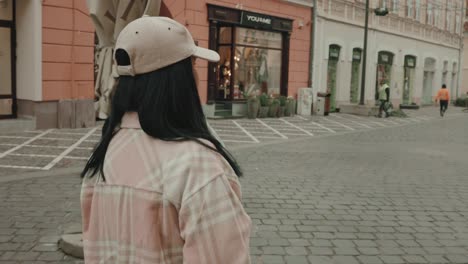 retrato lateral de una chica genial con gorra caminando en la ciudad de brasov en rumania