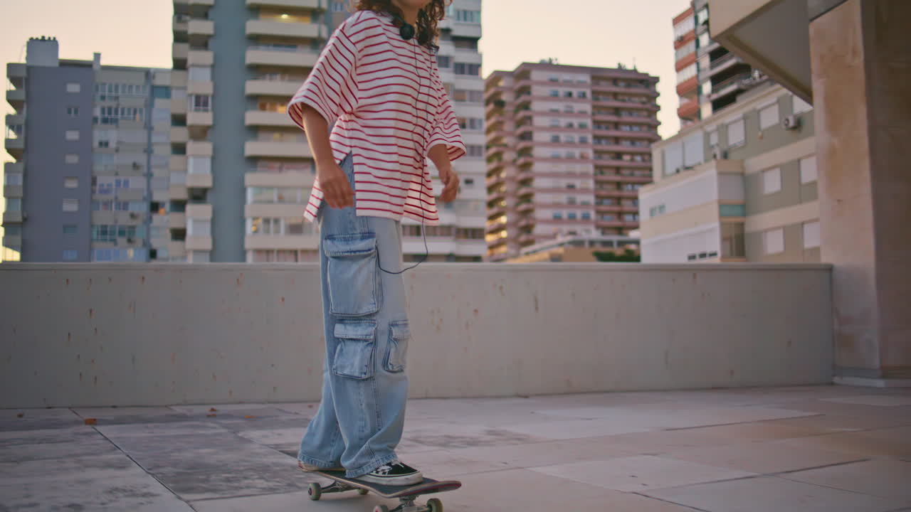 저녁 거리에서 스케이트보드를 연습하는 세련된 여성. 여자 스케이트 타는