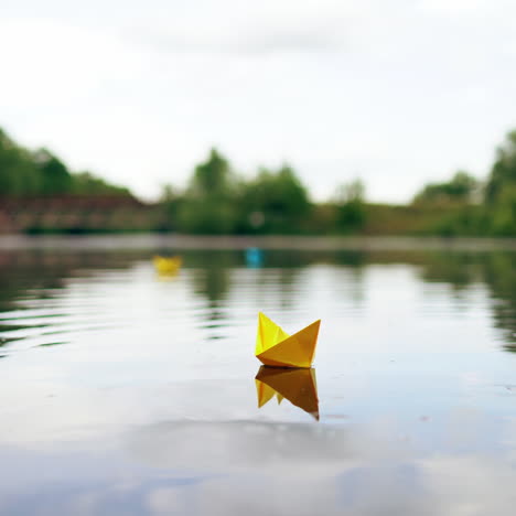 yellow paper boat is sailing on water surface under the evening sky. origami ship made of yellow paper is swimming on the river at sunset.