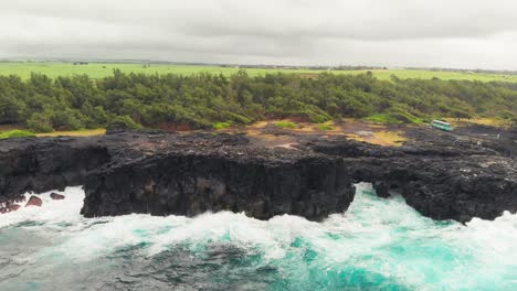 turquoise blue waters of the indian ocean crashing on rugged cliffs of pont naturel in mauritius