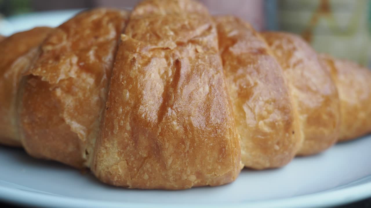primer plano de un croissant dorado en un plato blanco