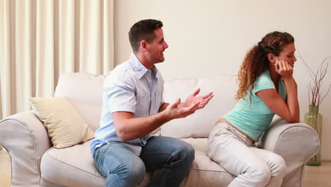 pareja sentada en el sofá luchando entre sí