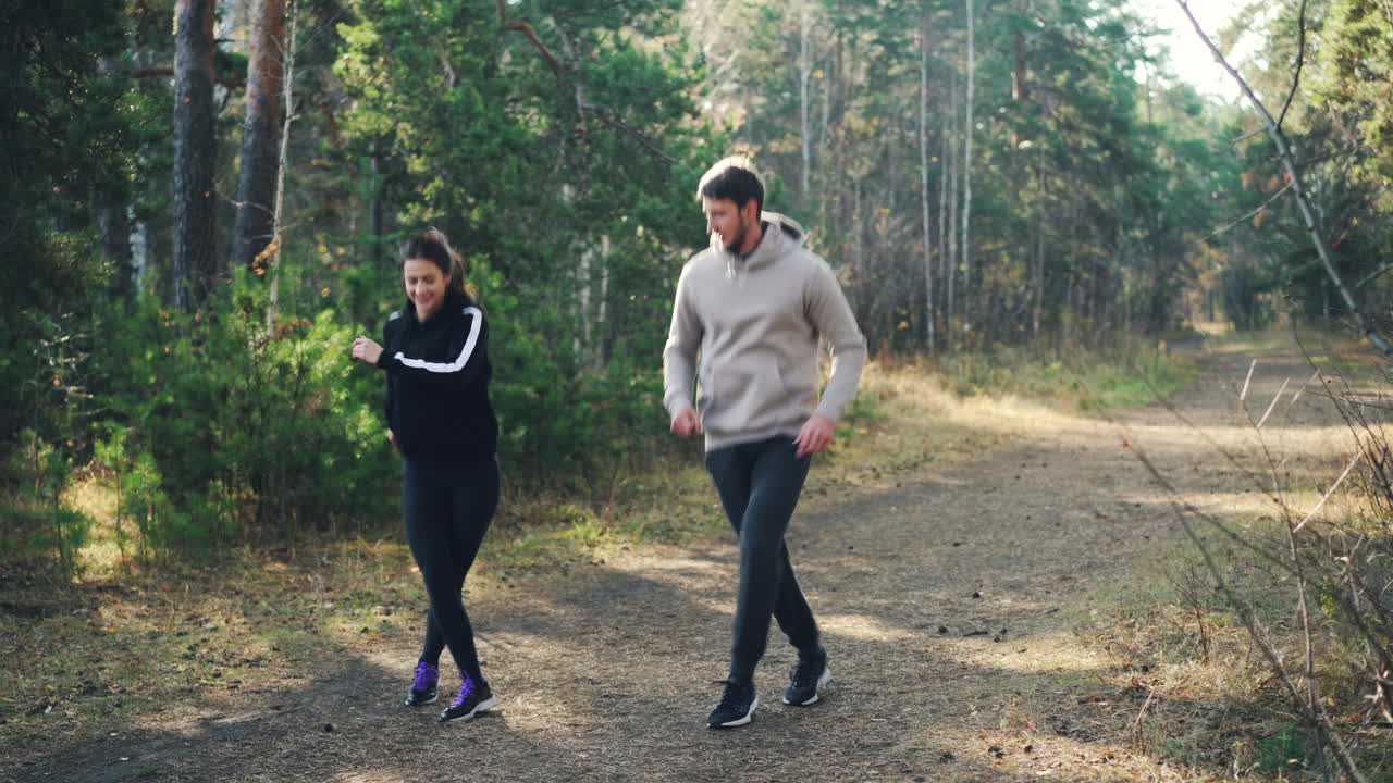 Coppia che fa jogging su un sentiero nel bosco in autunno