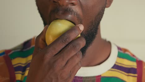 close up of a bearded afro american man biting and chewing green apple in slow motion