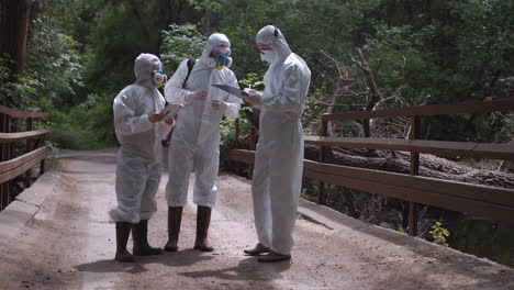 scientists in protective gear inspecting a bridge in a forest