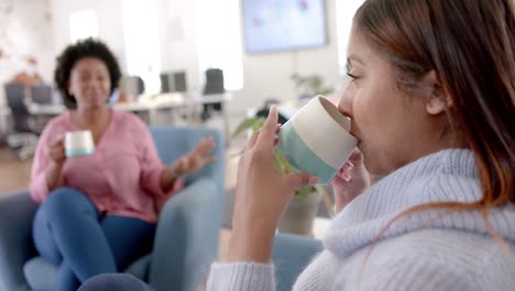 diversas compañeras de negocios bebiendo café y hablando en la oficina, en cámara lenta