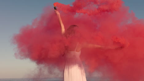 Mujer-Bailando-Con-Una-Bomba-De-Humo-Rosa-En-La-Playa-Al-Amanecer-Celebrando-La-Libertad-Creativa-Con-Un-Baile-Juguetón-En-Cámara-Lenta