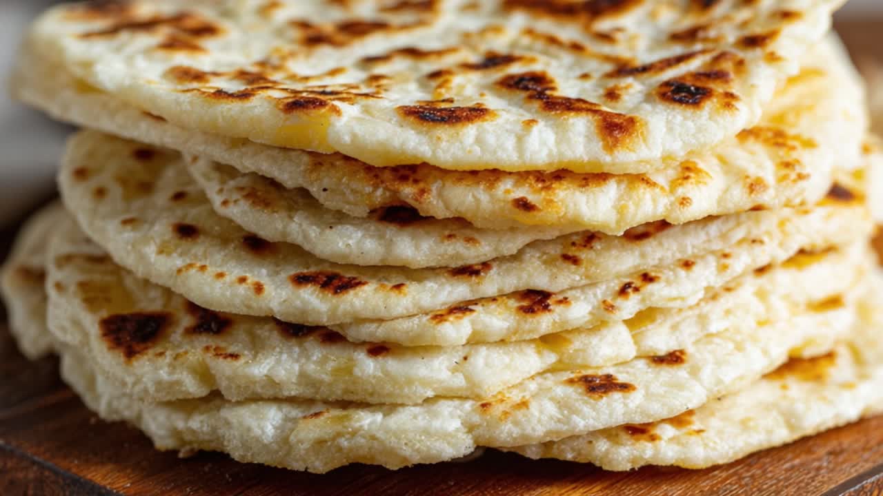 Красиво сложенная стопка свежеиспеченных лепешек с золотистой корочкой, демонстрирующая их мягкую текстуру и аппетитный вид — идеально подходит для любого приема пищи