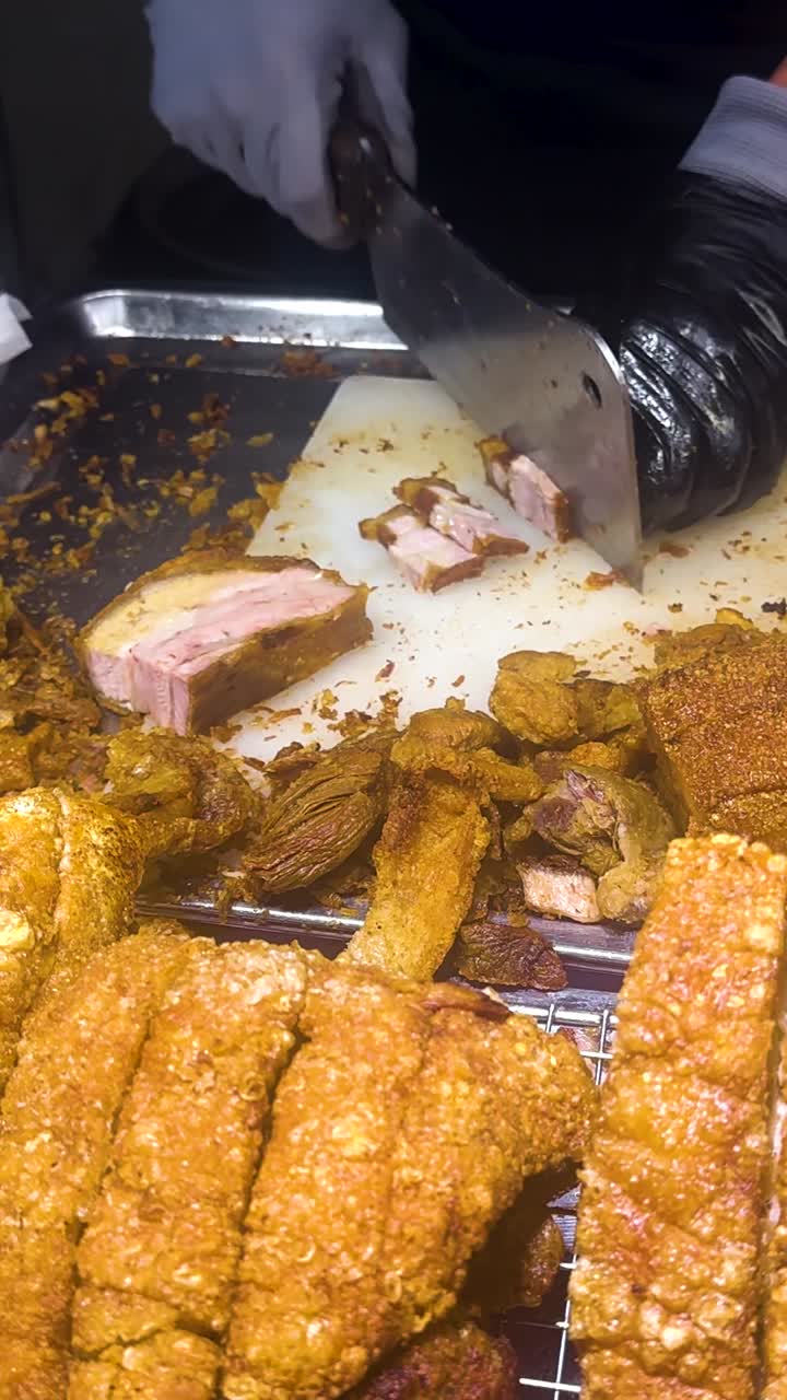 Un venditore affetta maiale croccante in un vivace mercato di Bangkok. L'illuminazione brillante evidenzia la consistenza dorata, catturando la vibrante scena del cibo di strada.