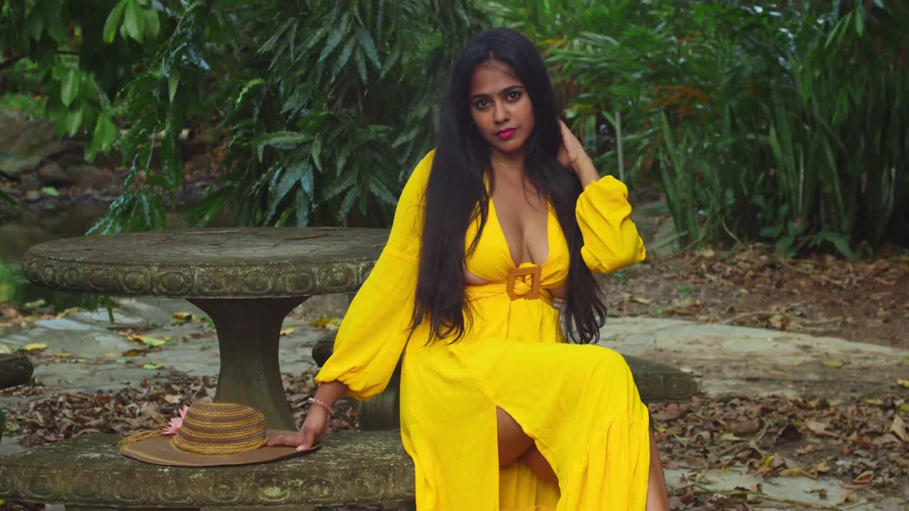 A lady in a flowing yellow gown posing on the vibrant green grounds of an ancient castle.