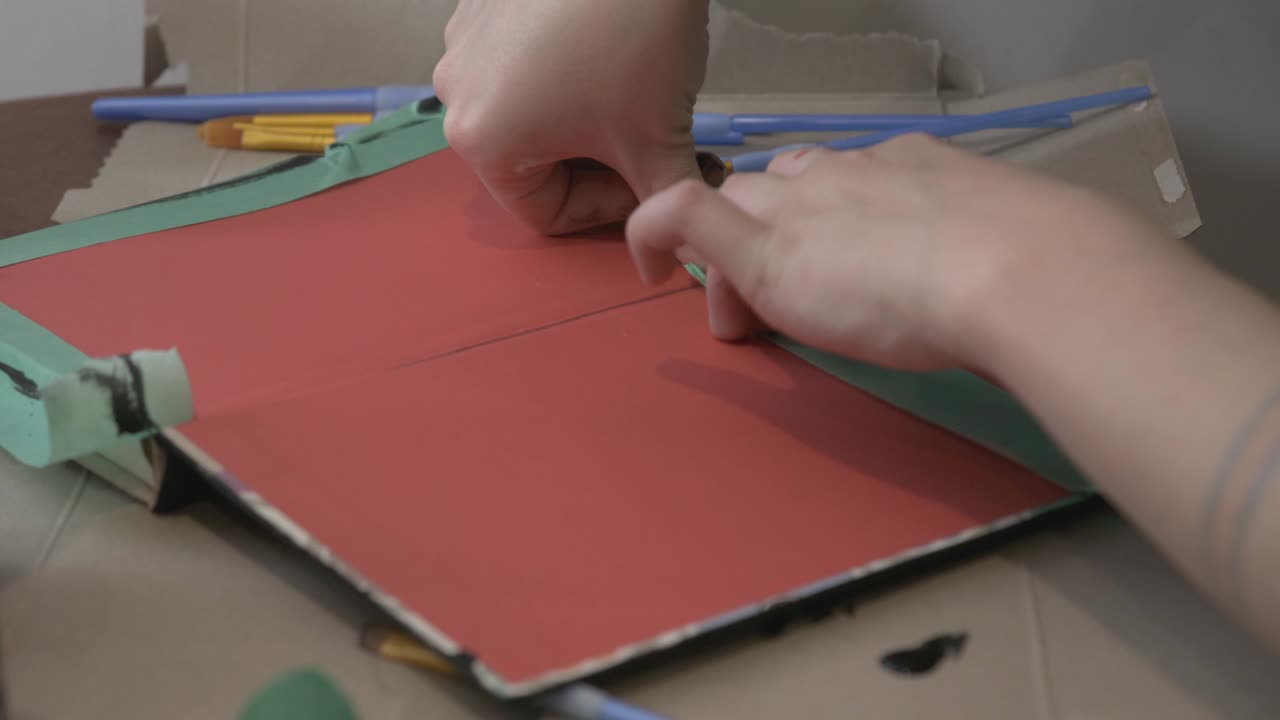 Hand Sticking Painters Tape At The Edge Of A Board - Closeup shot